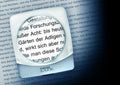 Ultra flat, circular magnifying lens with square, clear casing. Displayed on page, magnifying text.