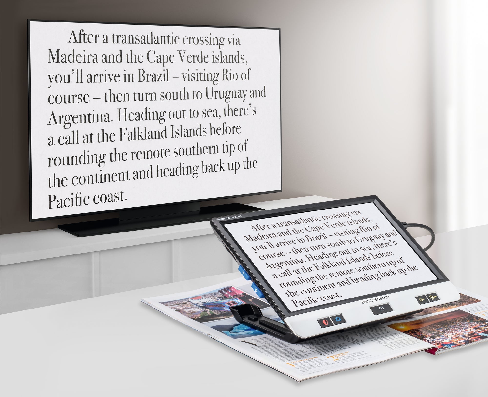 Visolux Digital XL FHD, digital magnifier with large screen, black outer casing and black selection buttons along the bottom of screen, plugged into and transmitting image onto television screen.
